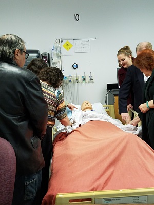 People surrounding a simulation manikin in a hospital bed